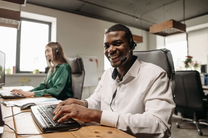 Un conseiller d'agence souriant à son bureau, casque sur les oreilles
