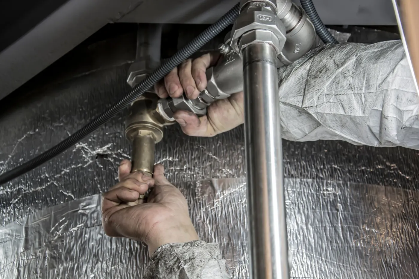 Les mains d'un plombier sur une canalisation